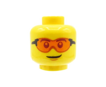 Głowa figurki LEGO w kolorze żółtym, męska, okulary przezroczyste pomarańczowe, delikatny uśmiech